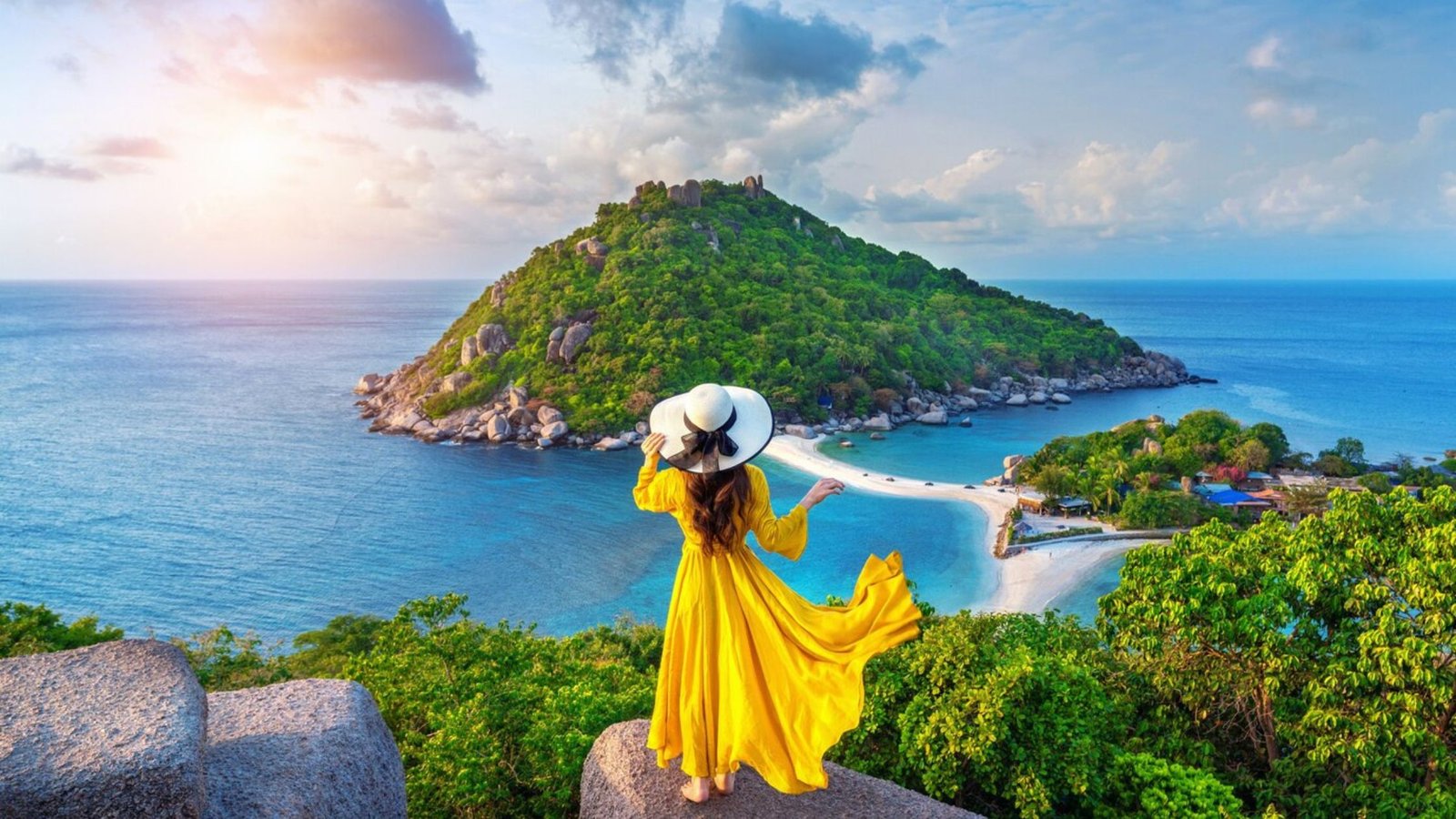 A picture of a woman wearing a yellow dress with a white hat looking as mountain